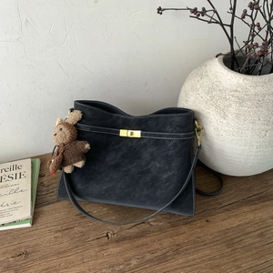 Détail du sac cabas en cuir noir avec surpiqûres blanches et fermoir rotatif doré