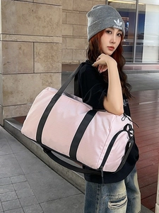Large pink travel bag with shoulder strap and wet dry separation shown with model
