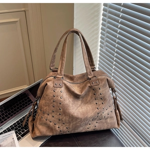 Détail du grand cabas vintage en cuir marron avec des rivets argentés et texture souple