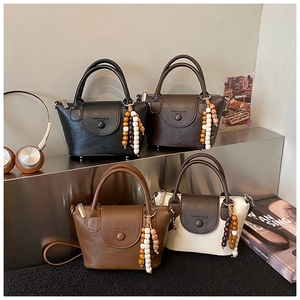 Detail view of four mini crossbody bags in leather with wooden bead tassels