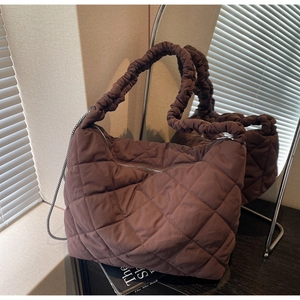 Detail of coffee brown quilted puffer tote bag with ruffled shoulder strap and silver zipper
