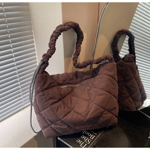 Macro view of oversized quilted puffer tote bag with ruched handle and checkered cord detail
