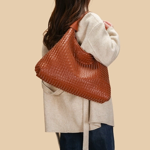Borsa a spalla in pelle intrecciata marrone con tracolla larga indossata da una modella