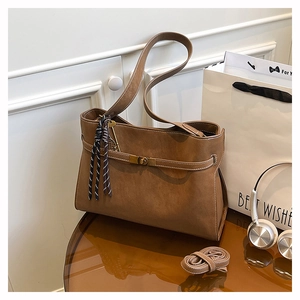Detail of a brown tote bag with white contrast stitching and a metal twist-lock closure