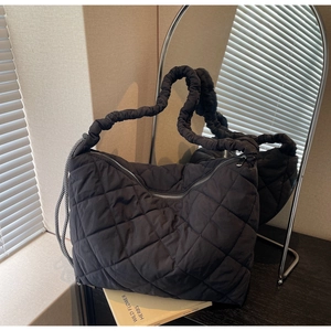 Detail of black quilted shoulder bag with ruched strap and stylish silver zipper closure