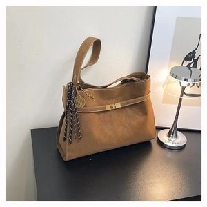Close-up of tan matte leather tote featuring gold twist lock and white contrast stitching