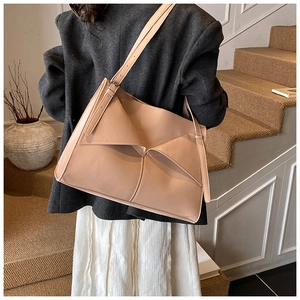 Dettaglio laterale della borsa tote in pelle PU beige con piega geometrica su modella