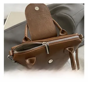 Detail view of brown faux leather bag showing silver metal zipper and magnetic snap closure