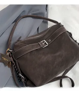 Detail of brown suede tote bag with metal buckle strap and star charm on grey blazer