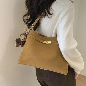 Détail du sac fourre-tout en daim jaune moutarde avec surpiqûres et pendentif tricoté