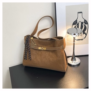Detail of matte suede tote bag with golden twist lock and stylish tennis racket pendant