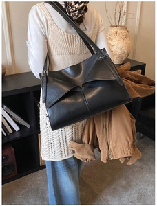Dettaglio posteriore di una borsa tote nera geometrica indossata a spalla in uno studio retrò