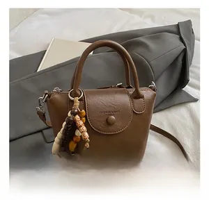 Detail view of dark brown PU leather handbag featuring wooden beads and secure zipper