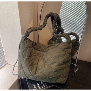 Close-up of olive green quilted tote bag with scrunchie strap and braided rope detail