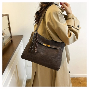 Detail of dark brown tote bag with matte texture, golden swivel lock and tassel charm