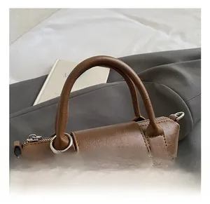 Detail of soft brown leather handbag with round handle and colorful wooden beads charm