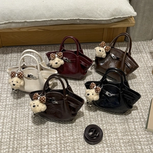 Close-up of five mini pleated leather buckets with bear charms and detachable straps