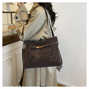 Detail of dark brown matte tote bag with contrast stitching and decorative charms