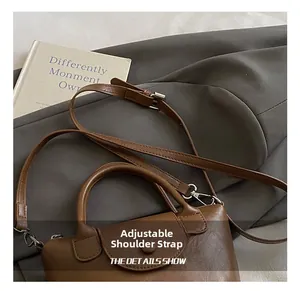 Detail of adjustable strap and silver metal buckle on brown vintage leather handbag