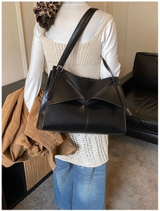 Dettaglio della borsa tote in pelle nera con design a patta pieghevole asimmetrica