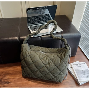 Detail view of military green quilted puffer bag with signature diamond stitch and gathered strap