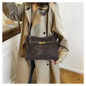 Detail of matte dark coffee tote bag with gold buckle on a beige trench coat