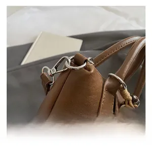 Macro shot of brown leather bag featuring silver metal hook and bohemian beaded tassels
