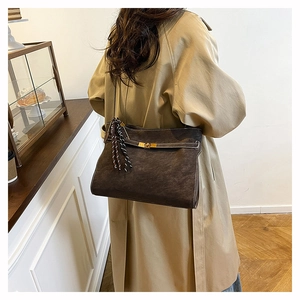 Detail view of large dark brown suede tote bag with golden lock and fringe pendant