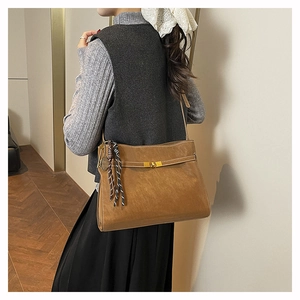 Detail of vintage brown leather tote bag with gold twist lock and silk scarf decor