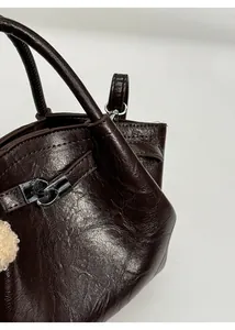 Close-up of brown bucket bag with shiny oil wax finish and silver metal ring detail