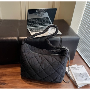 Detail of black quilted tote bag with ruffled cloud strap and decorative side cords