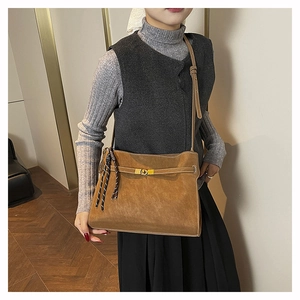 Caramel matte leather tote bag with gold swivel lock and tassel shown on model