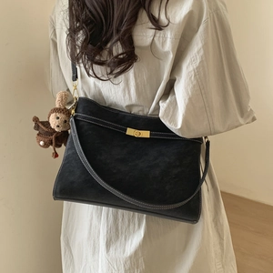 Détail du sac sous le bras noir avec surpiqûres contrastées et breloque animal tissé