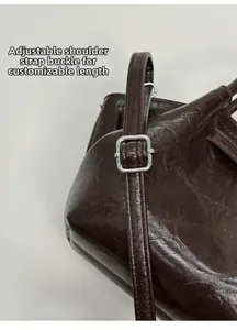 Detail view of adjustable silver buckle and glossy dark brown leather strap of the bag