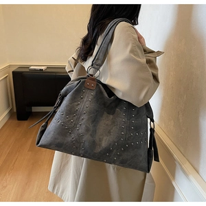 Gros plan sur un grand sac cabas vintage gris avec rivets et texture daim mat doux