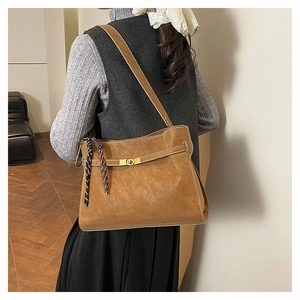 Detail view of large brown matte tote bag featuring gold clasp and woven tassel detail