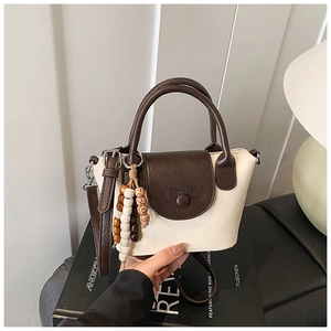 Detail of soft cream PU leather crossbody bag with brown accents and beaded charm