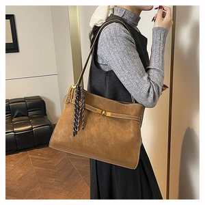 Detail of retro brown matte tote bag featuring gold twist lock and racket pendant