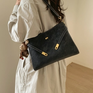 Détail d'un sac cabas noir mat avec coutures en V et boucles métalliques dorées élégantes