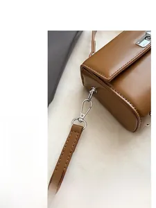 Close-up of silver metal hooks and precise stitching on the brown leather handbag