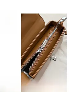 Top view detail of brown leather handbag featuring a smooth silver metal zipper closure