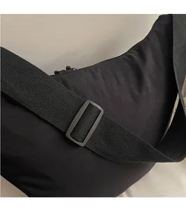 Detail of adjustable wide fabric strap and durable nylon texture on a black crossbody bag