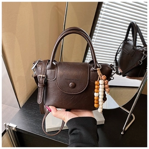 Detail of dark brown leather mini bag featuring beaded tassel and logo embossing