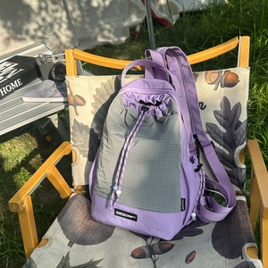 Dettaglio di uno zaino viola con coulisse su una sedia di legno con set da campeggio