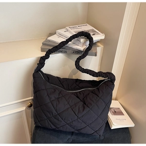 Close-up of black quilted hobo bag with padded cloud strap and zip closure detail