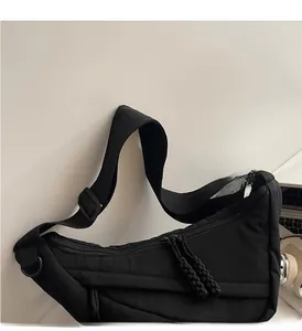 Detail of durable black nylon crossbody bag featuring adjustable wide strap and dual zippers
