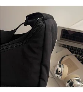 Close-up of soft black nylon hobo bag texture with zipper and wide strap detail