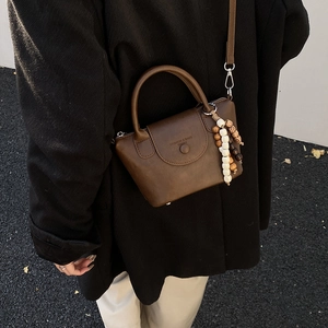 Detail of soft dark brown leather crossbody bag with wooden bead charm and stamp