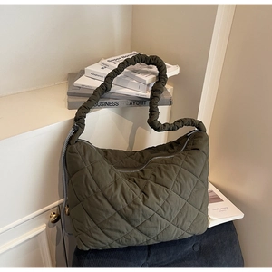 Detail of dark olive quilted tote bag featuring a scrunchie shoulder strap and puffy texture