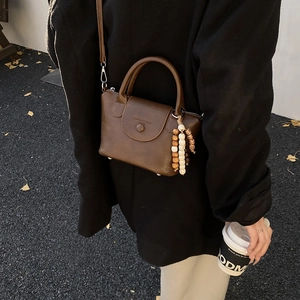Detail of vintage brown soft leather crossbody bag with ethnic beaded tassel charm